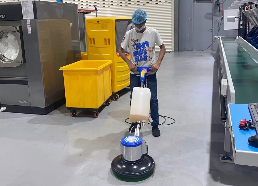 Nexo Cleaning team member scrubbing a factory floor